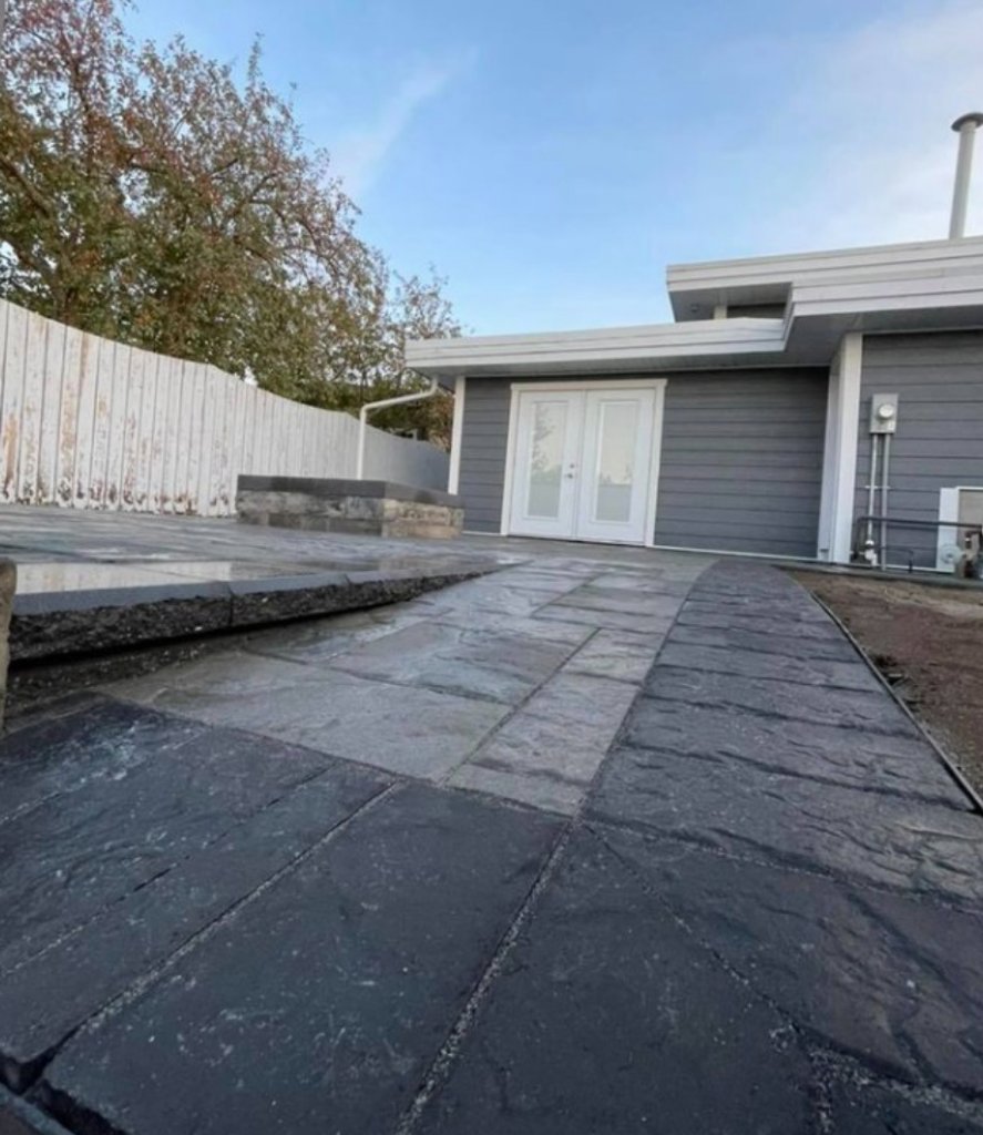 Modern patio and walkway with dark border stones leading to backyard