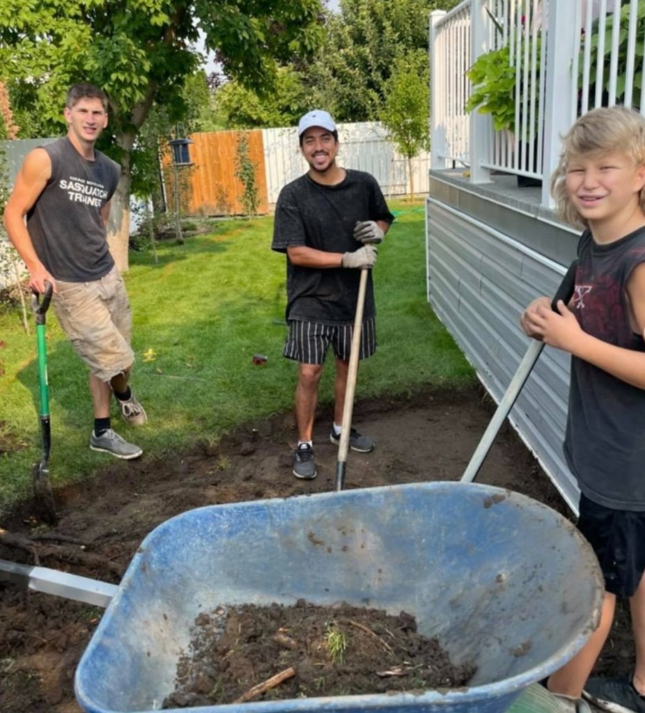 Landscape crew preparing soil and grading beside a home