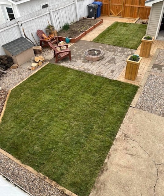 Backyard outdoor living space with lawn, patio stones, and fire pit