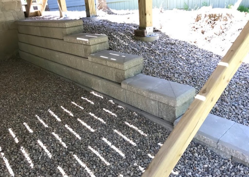 Block retaining wall and gravel area under a deck with clean cap stones