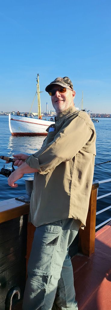 Medlem i camo-kasket fisker fra relingen