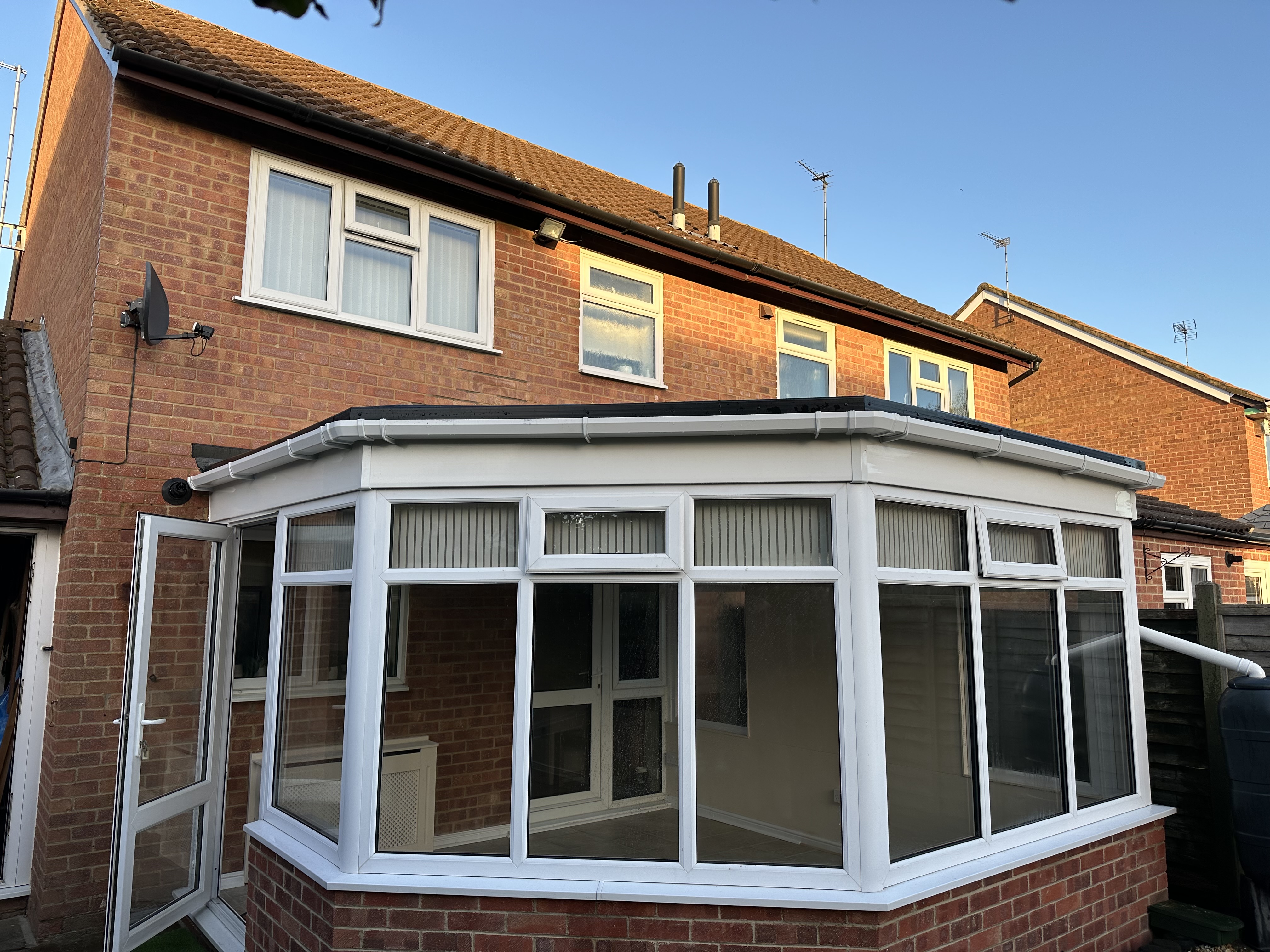 L-shaped conservatory with charcoal tiled roof under blue sky