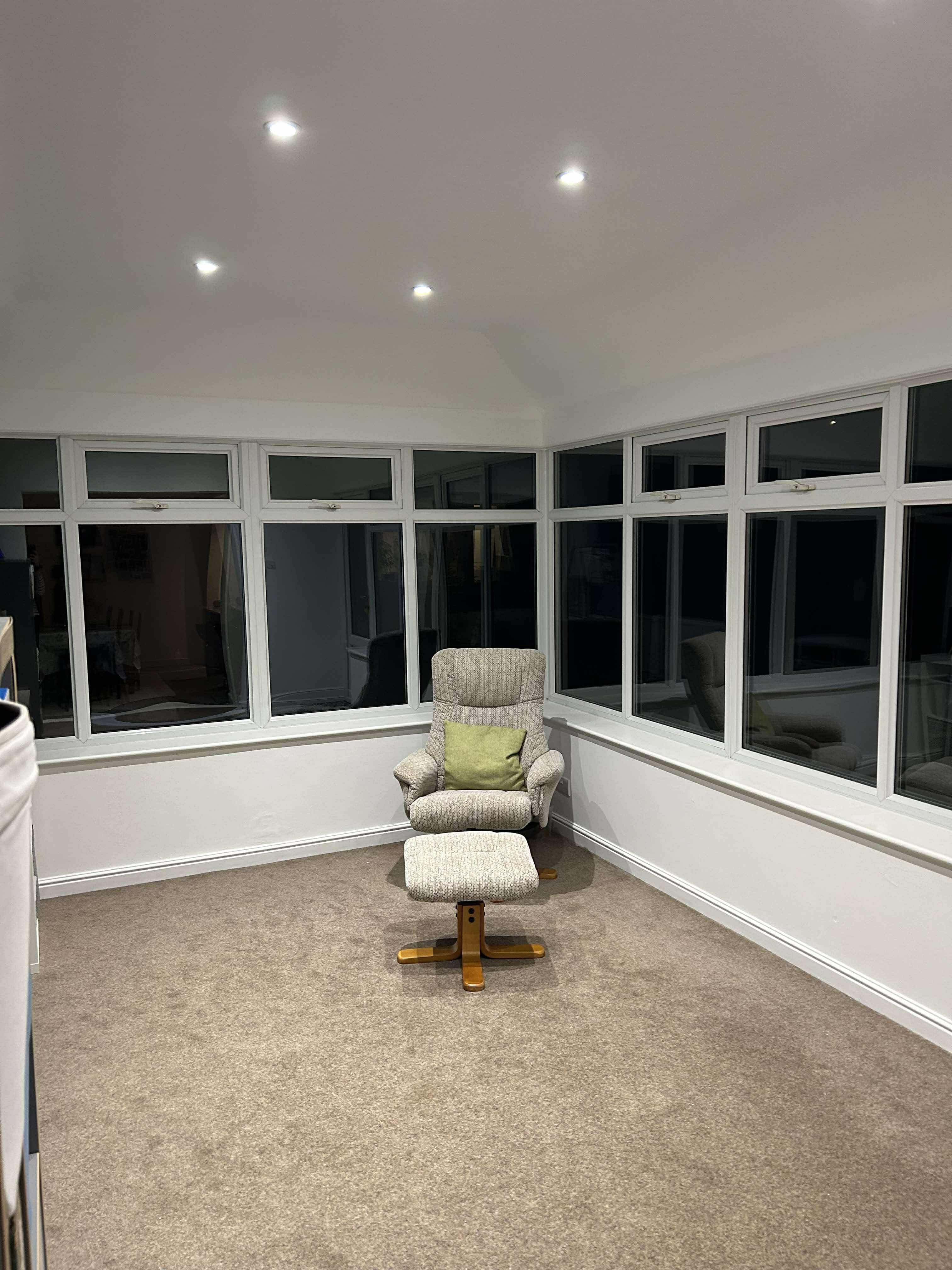 Cosy conservatory living space with recliner and plastered ceiling
