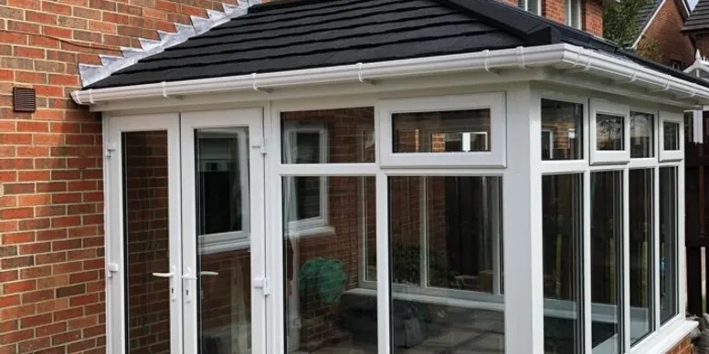 Finished conservatory with dark grey slate-effect tiled warm roof