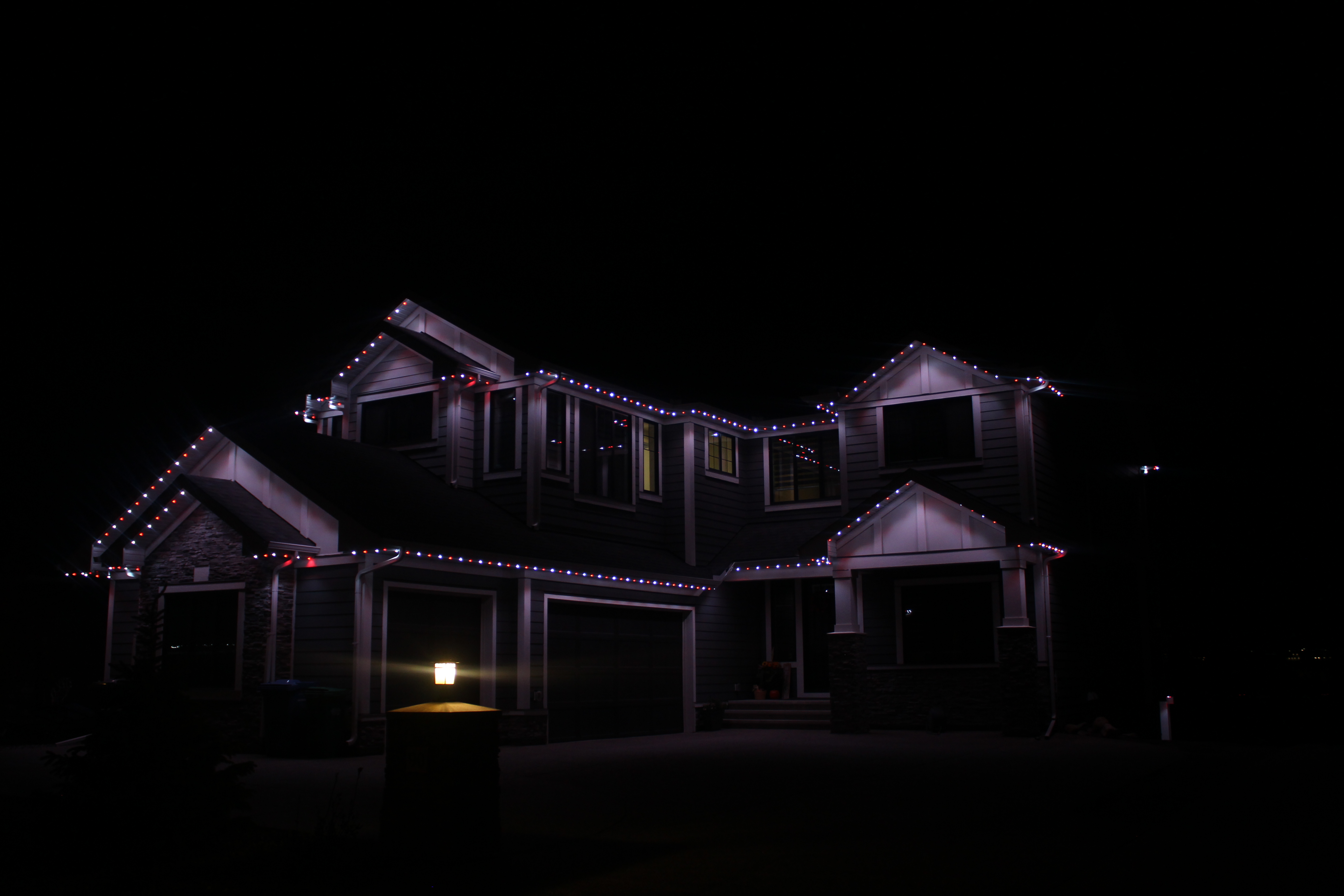 Full home exterior at night with red, white and blue permanent LED lighting on every roofline