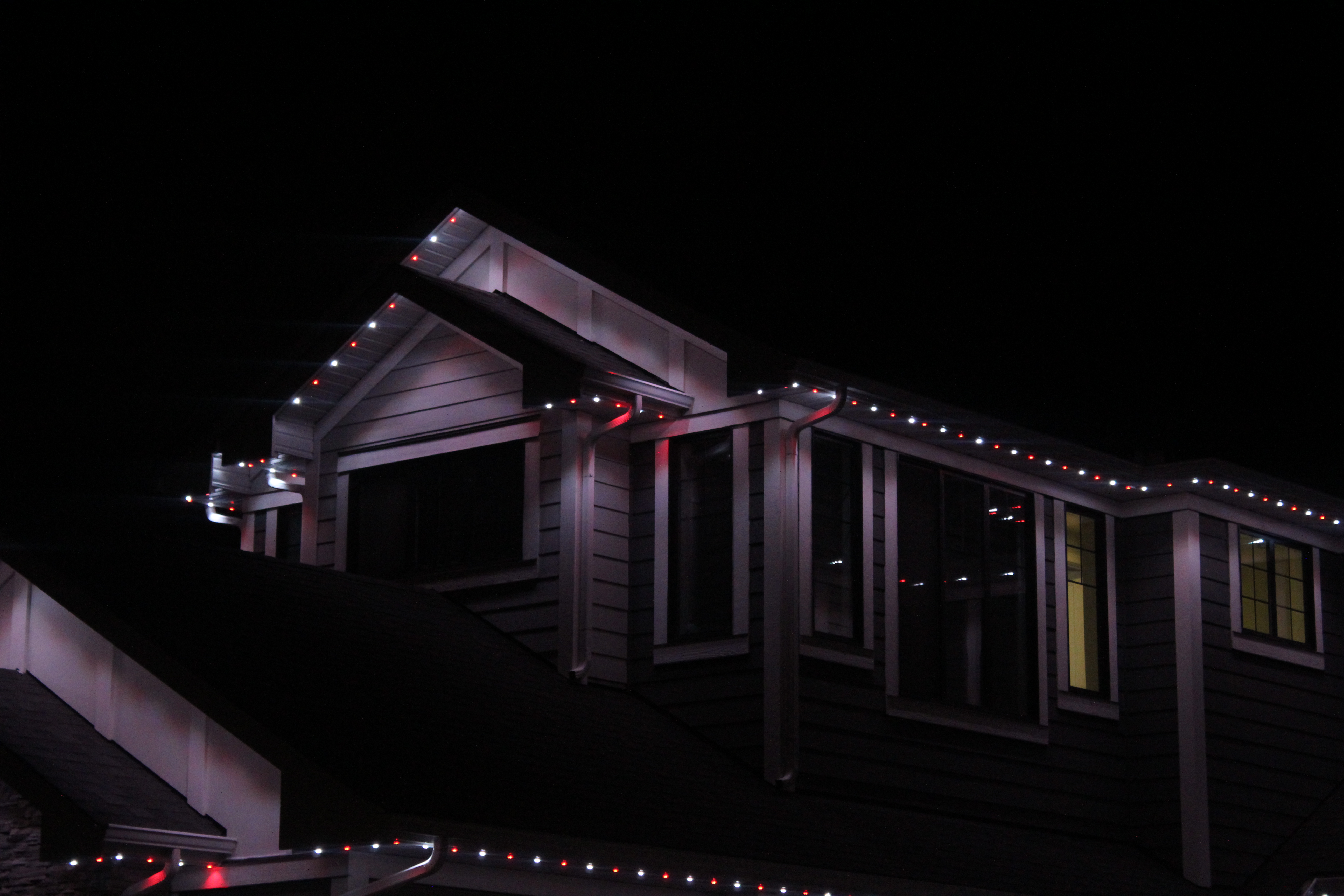 Upper rooflines and dormers lit with red and white permanent LED lights at night