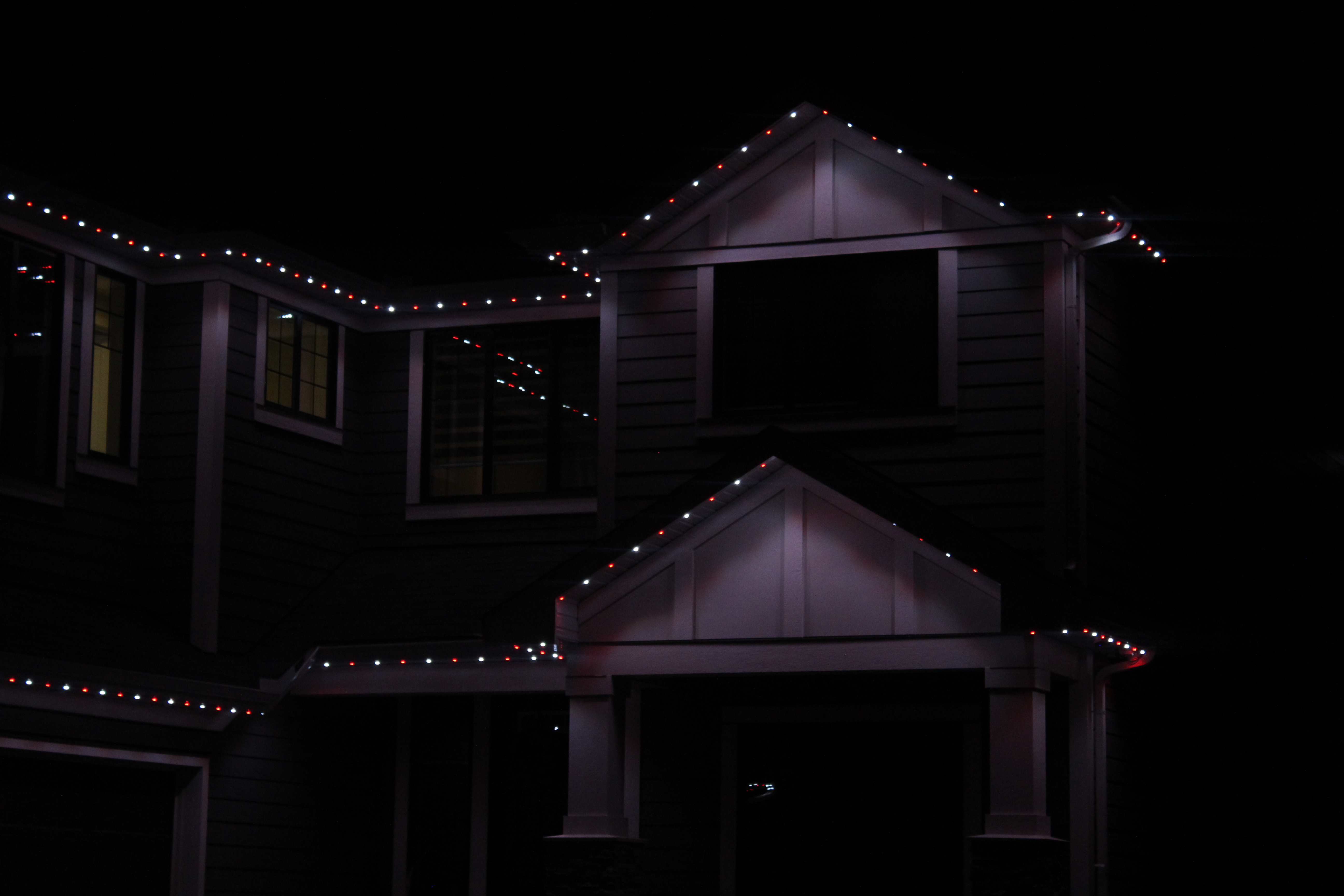Front gables and porch roofline highlighted with red and white permanent LED lights at night