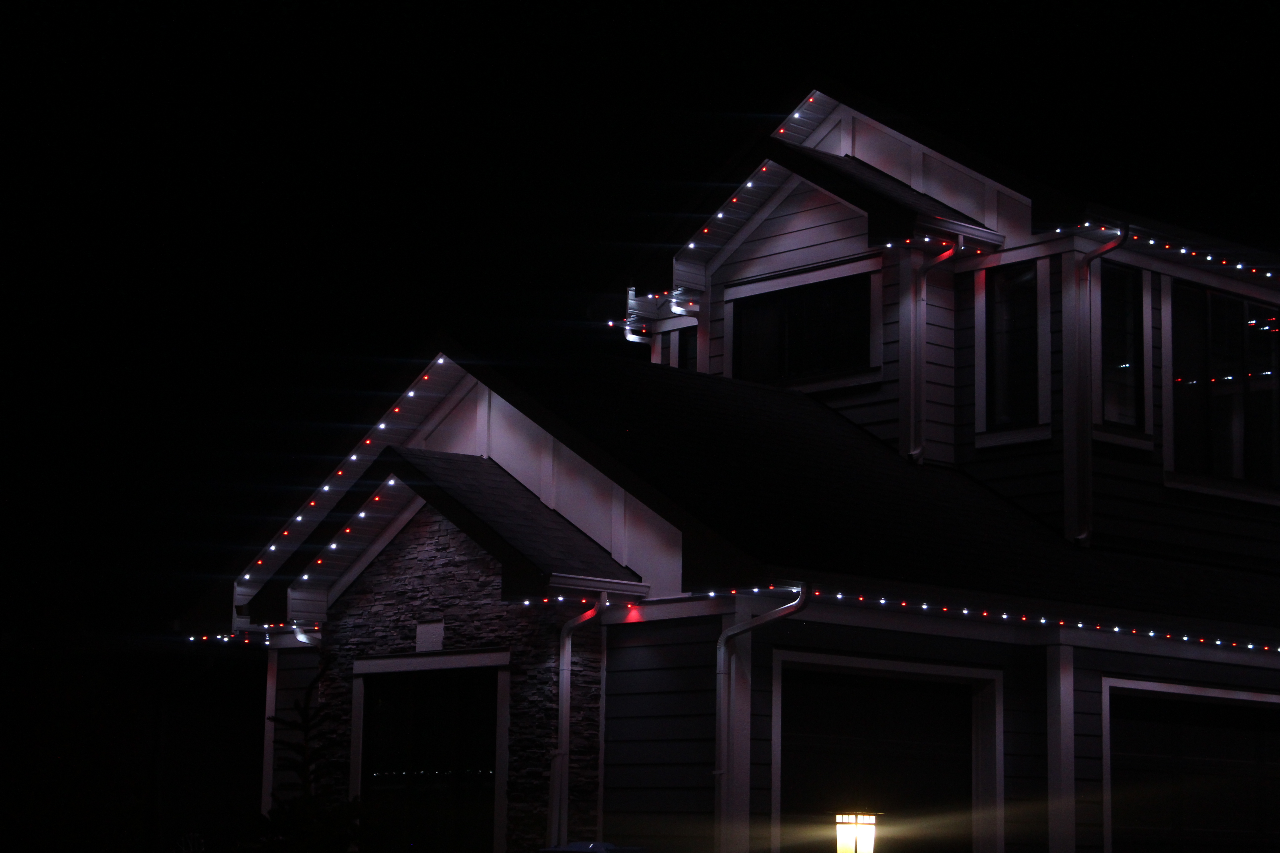 Gabled rooflines outlined in red and white permanent LED lights against a night sky