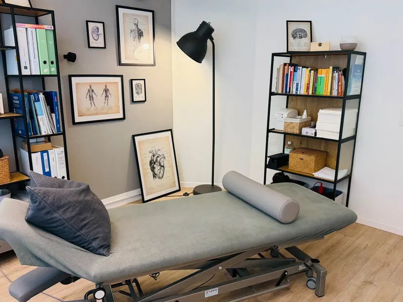 Behandlungsliege mit Stehlampe und Anatomie-Bildern in der Praxis in Weinfelden