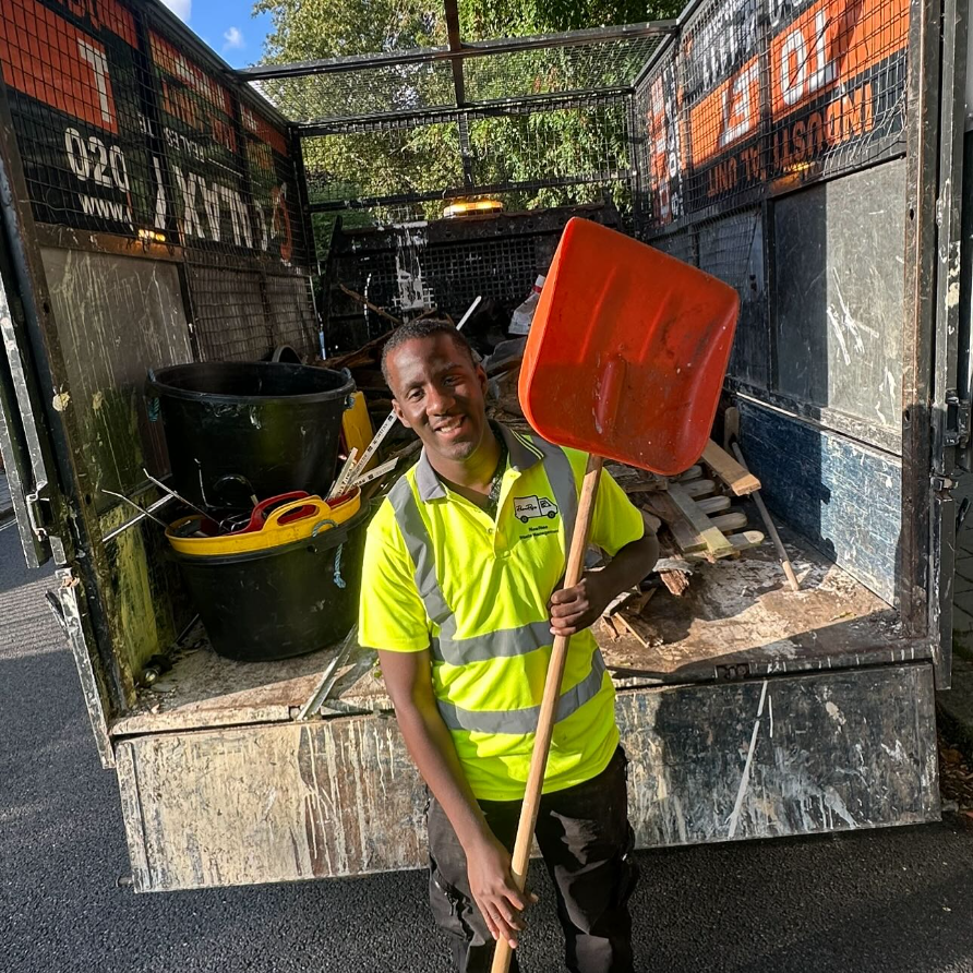 RicaRise team member in hi-vis with shovel at waste collection site