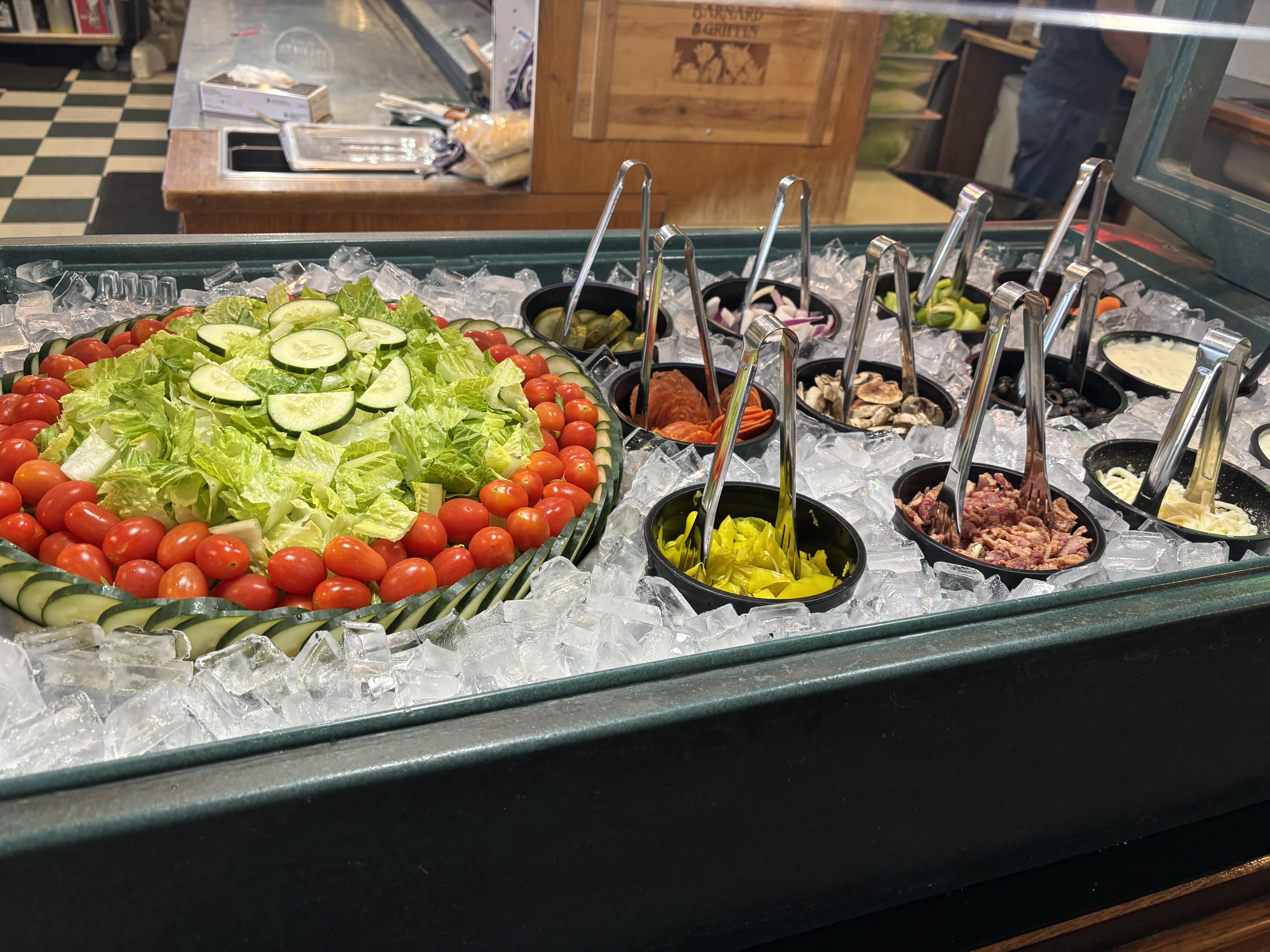 Brick House Pizza fresh salad bar with crisp greens, cherry tomatoes, cucumbers, and toppings nestled in ice