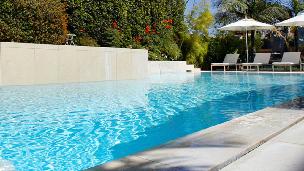 Resort pool terrace — limestone coping, overflow edge, tropical bougainvillea and palm backdrop
