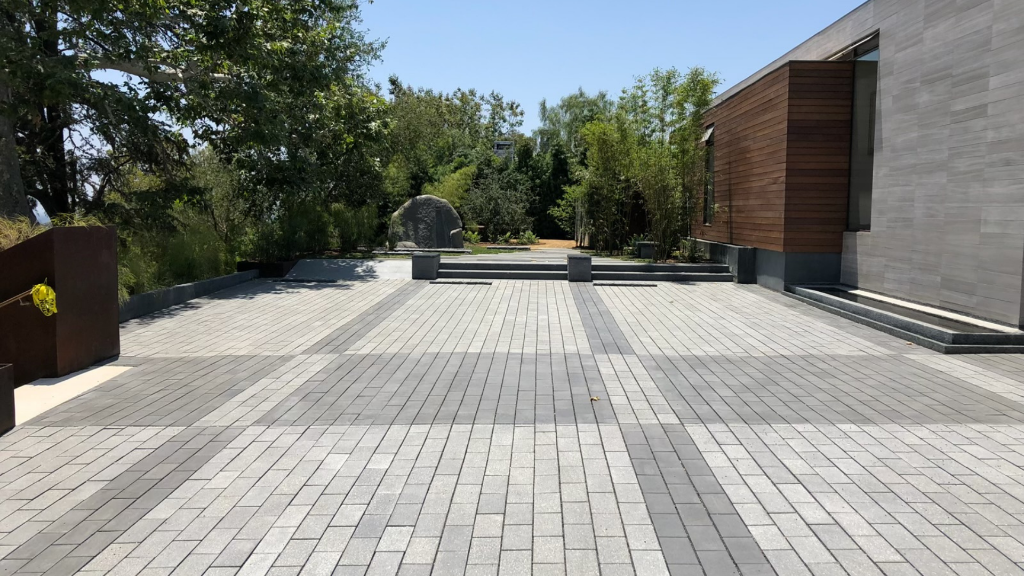 Motor court — large-format paver courtyard with boulder focal point and corten planters