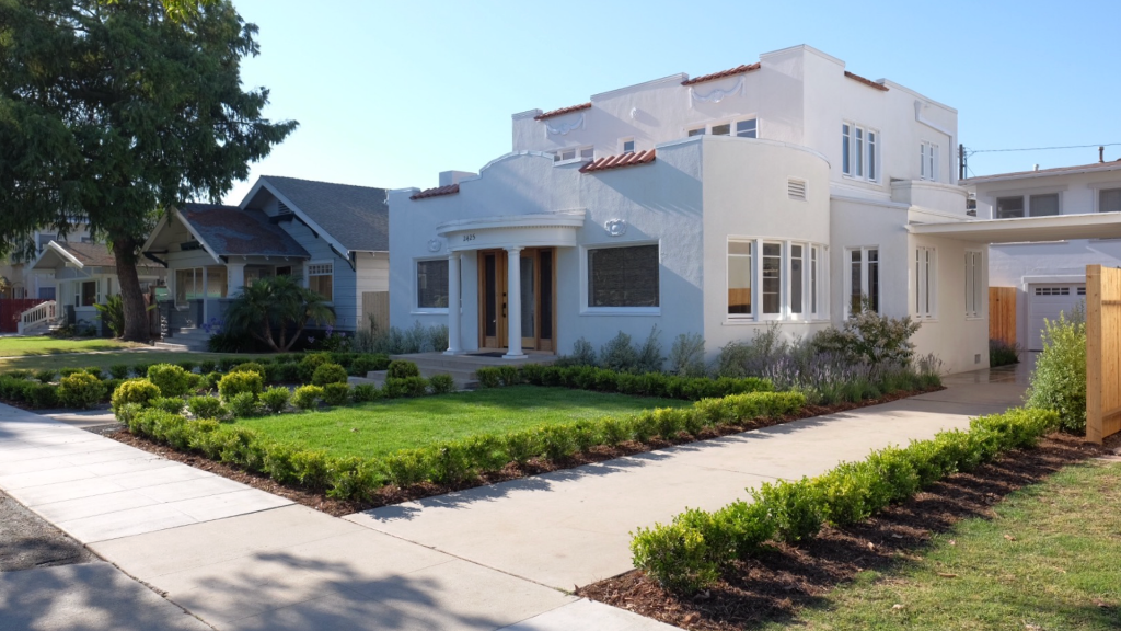 Spanish Revival exterior — symmetrical boxwood grid, lawn panel, and perennial border planting