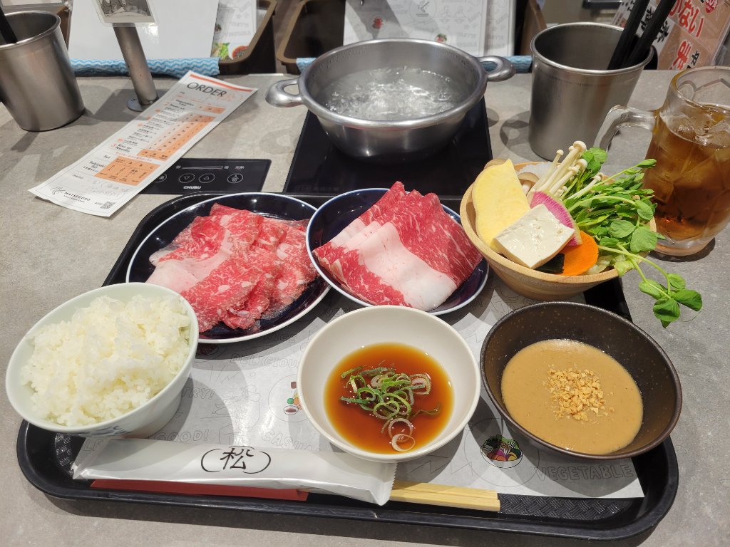 A sukiyaki hot pot meal with beef, vegetables, and rice