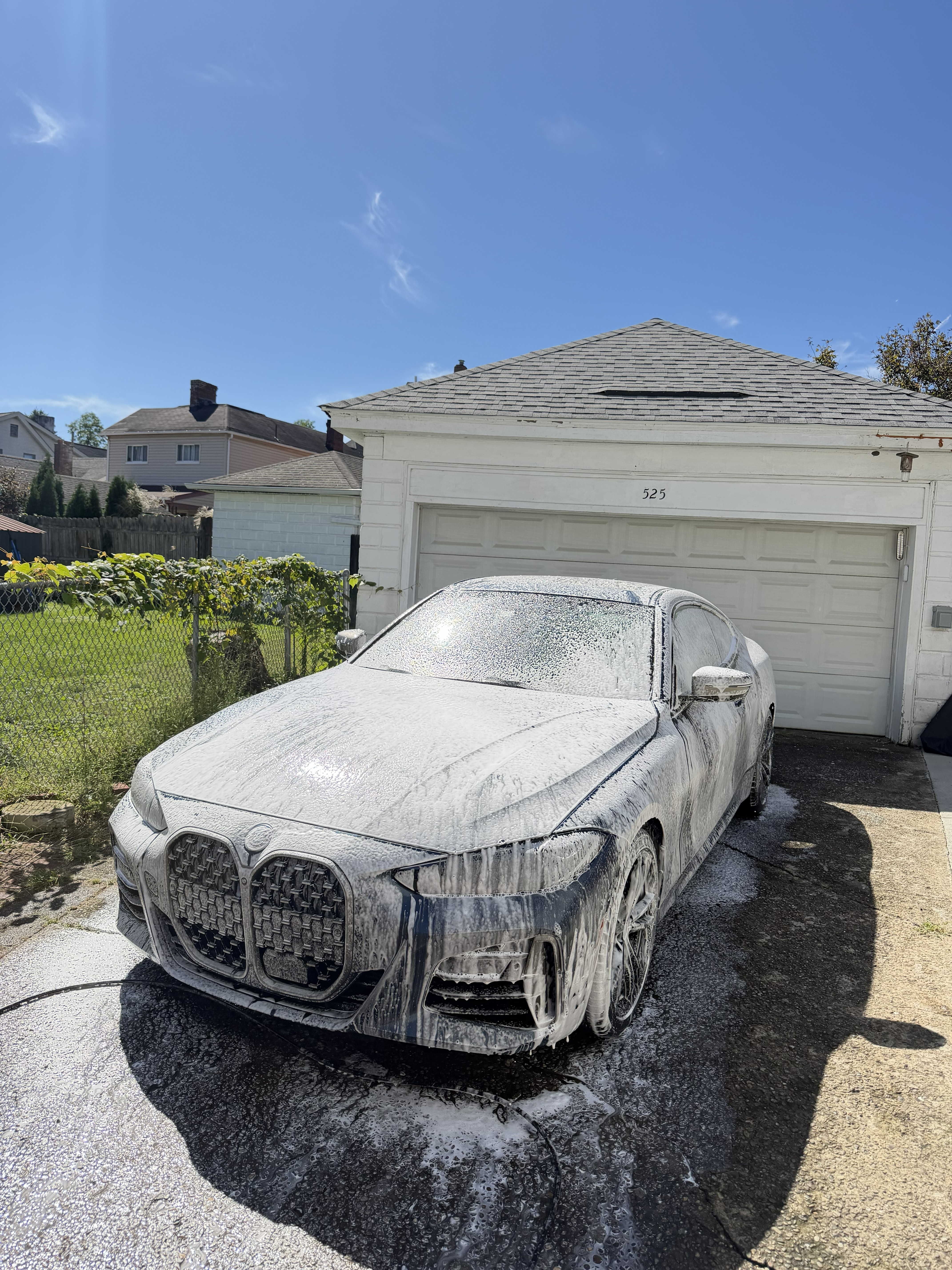 BMW sedan covered in thick white snow-foam suds during a mobile hand wash on a residential driveway in Fox Chapel, PA