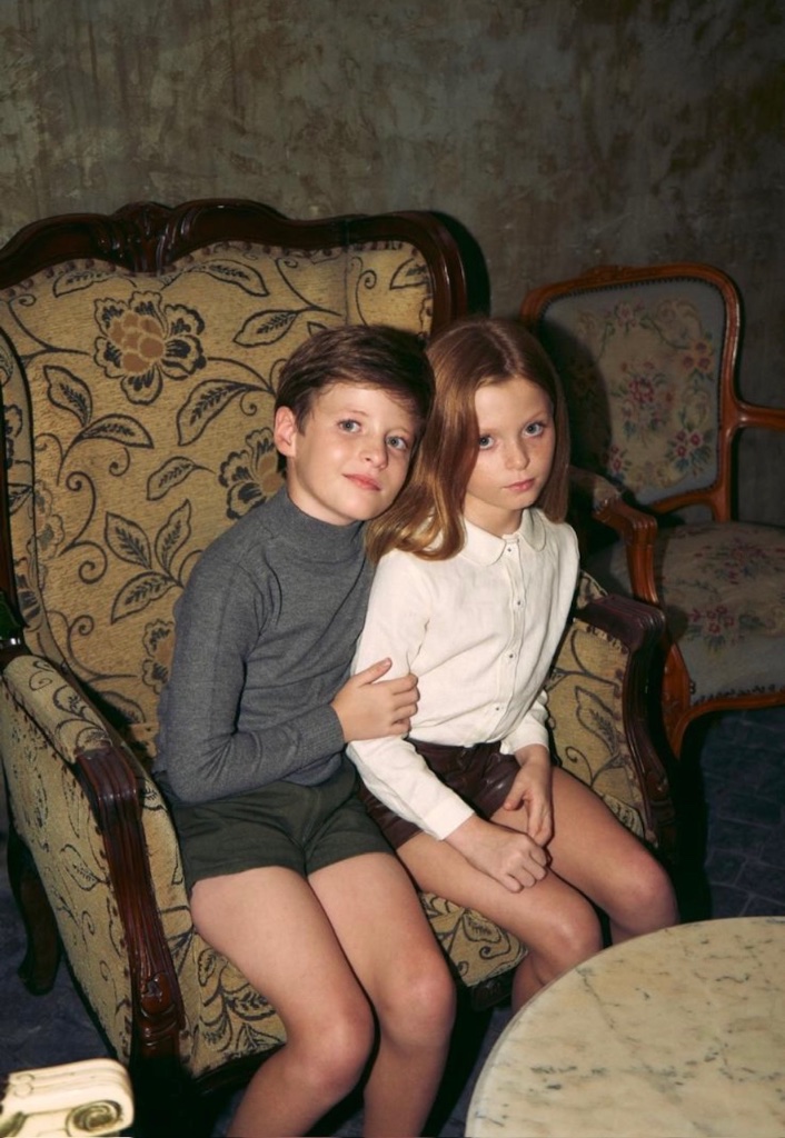 Children seated in antique armchair