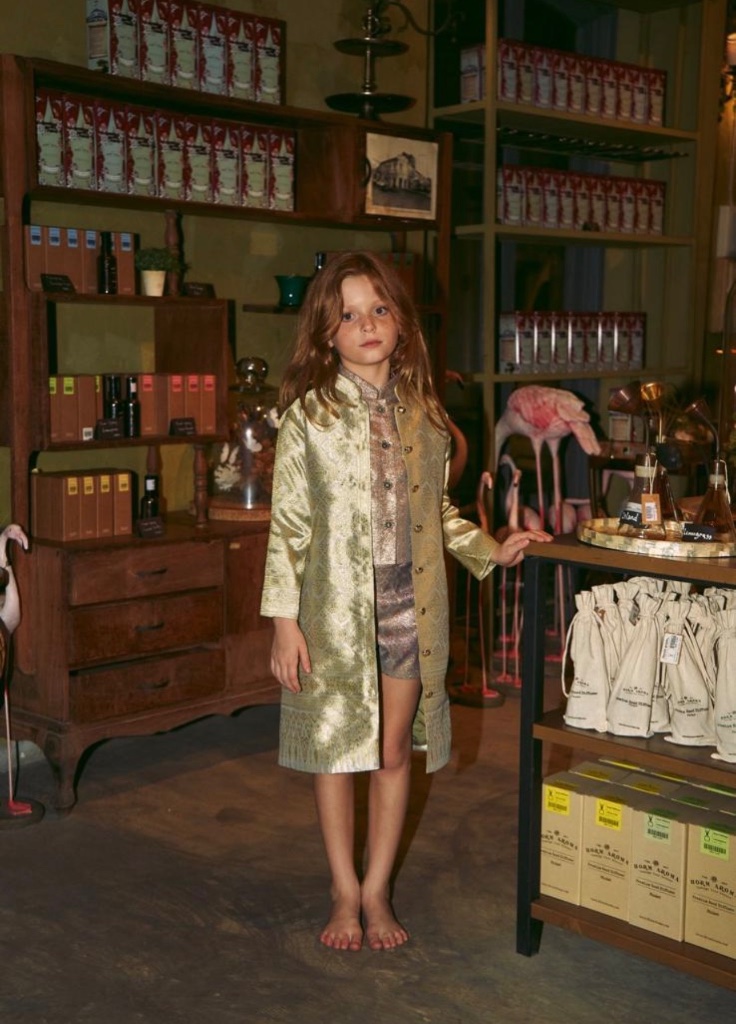Girl in gold brocade coat at a shop