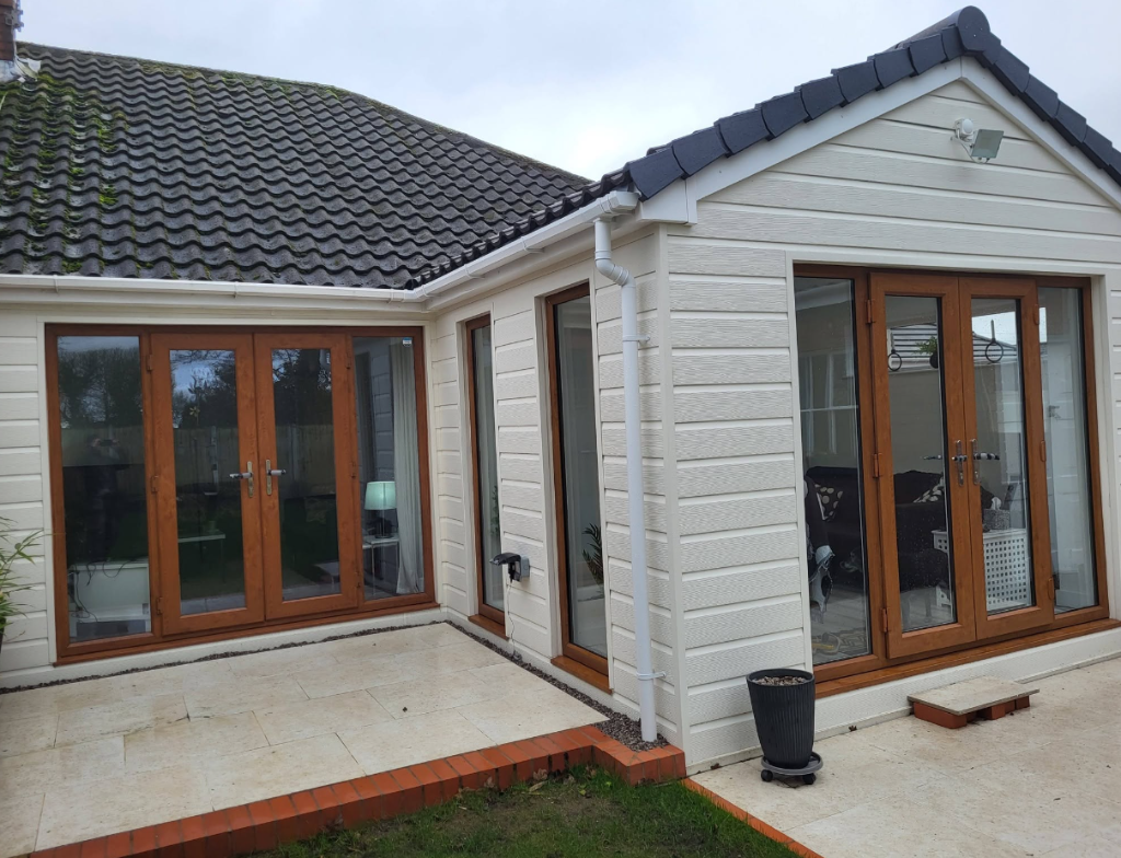 Home extension with white cladding, timber french doors and patio