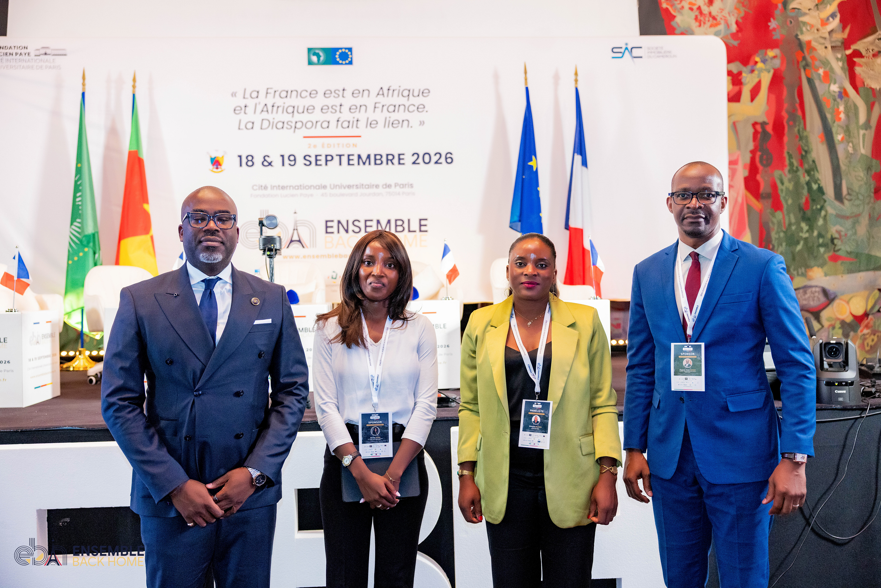 Quatre participants devant le backdrop officiel