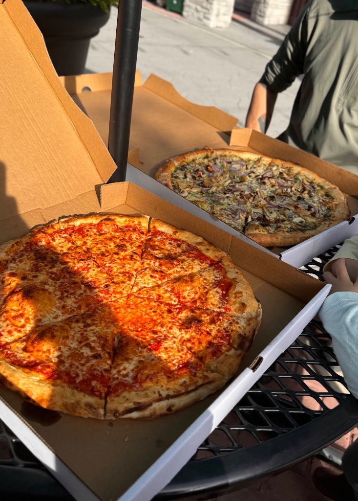 Two pizzas in boxes outdoors