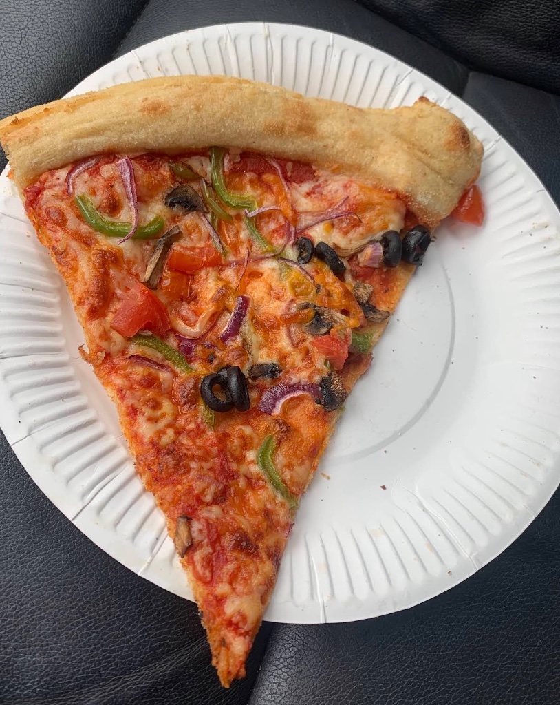 Veggie pizza slice on paper plate