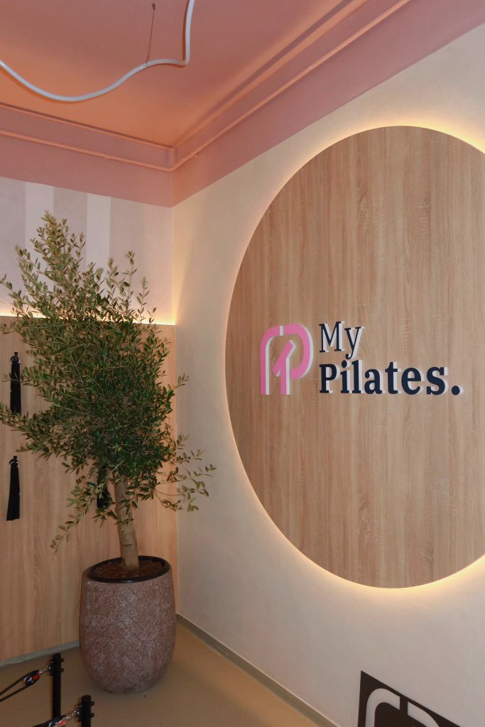 Logo My Pilates pe perete din lemn, cu iluminare ambientală și măslin decorativ