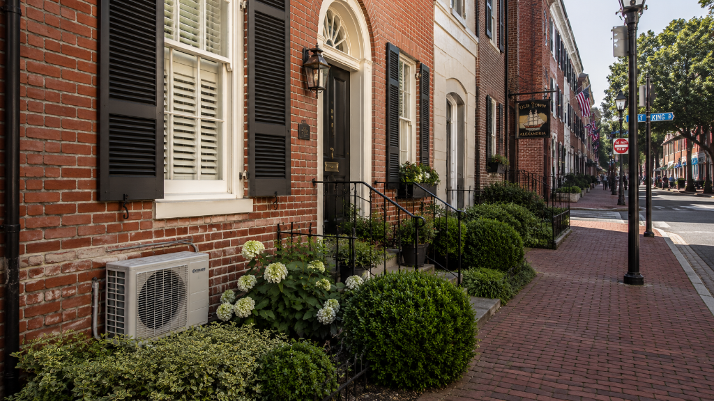 Red-brick Old Town Alexandria row house with white ductless mini-split outdoor unit against the brick wall