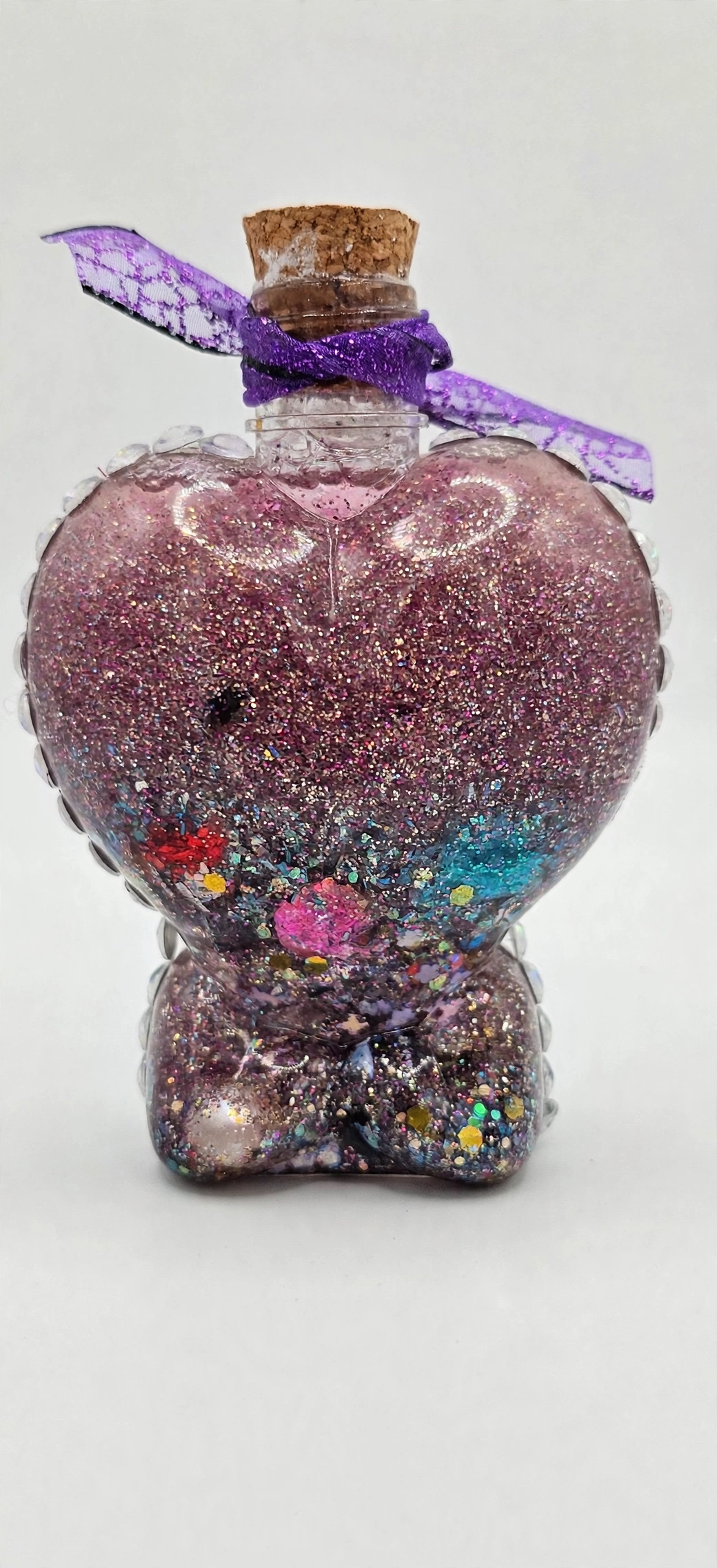 Heart chakra healing potion bottle with rose-pink glitter and purple ribbon for heart healing after a toxic relationship
