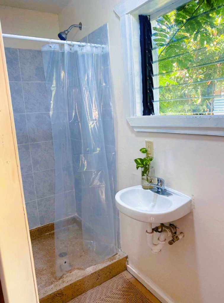 Bathroom with blue-tiled shower and window to greenery