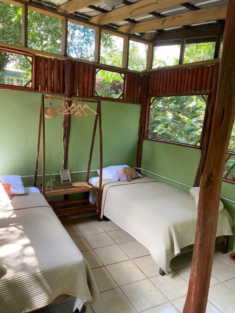 Sage green bedroom with two single beds and wooden clothing rack