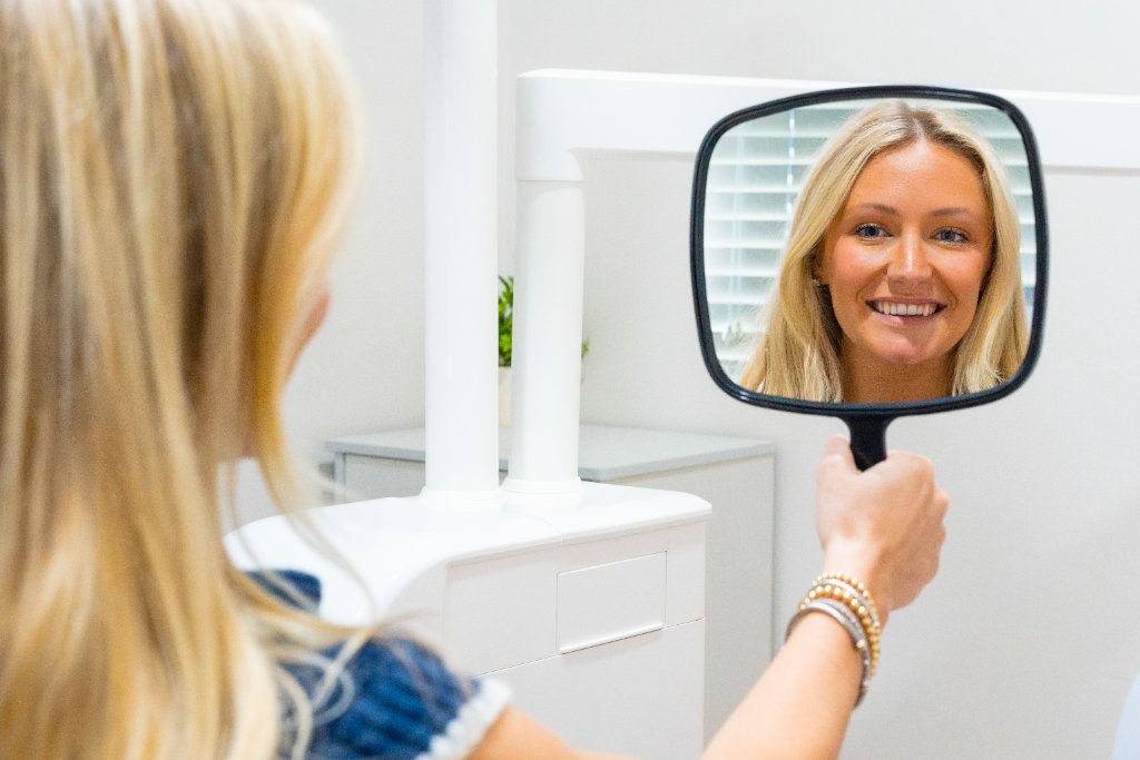 Patient admiring her smile in a hand mirror
