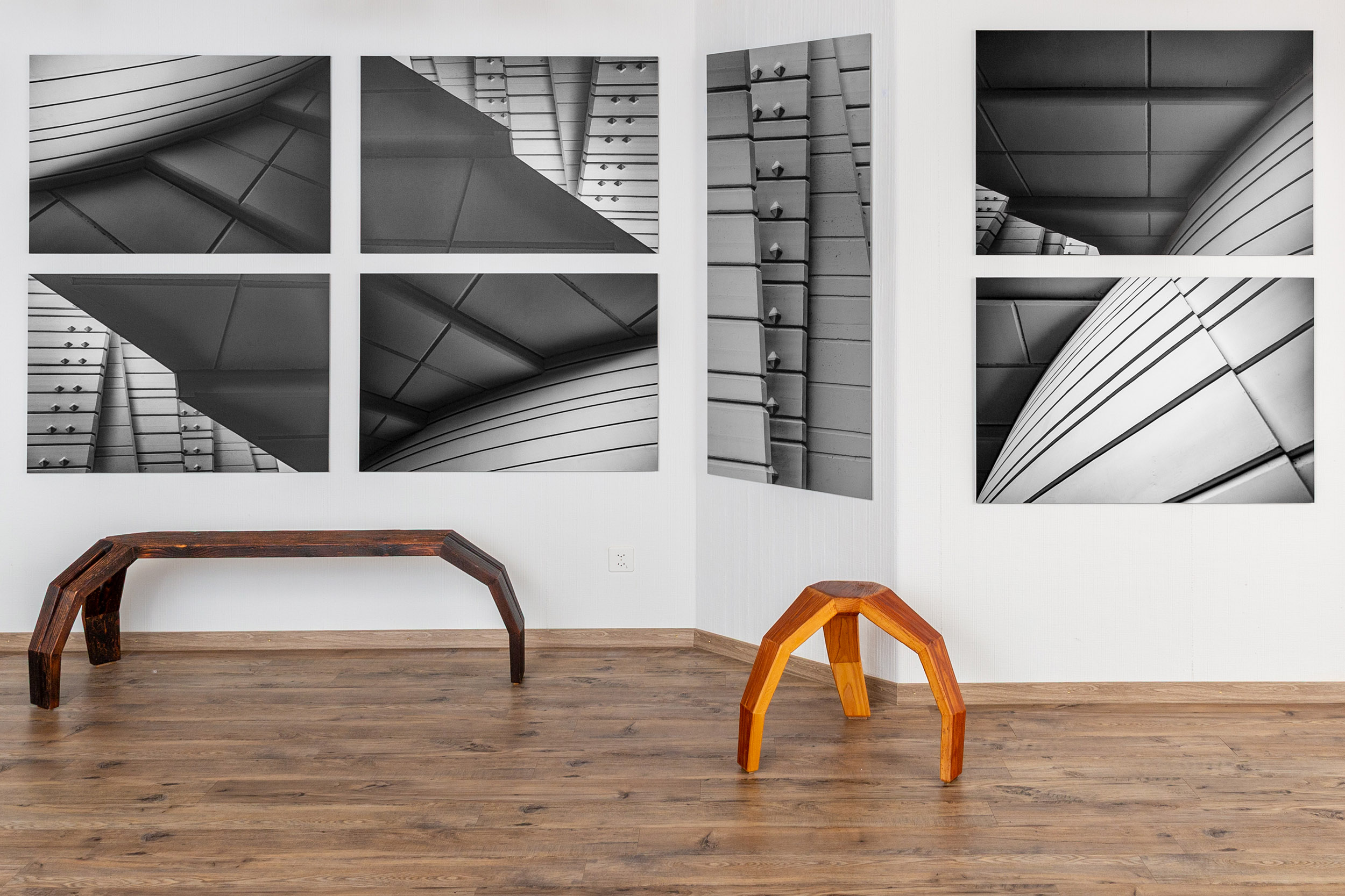 Architekturfotografien an einer weissen Wand mit Holzbank und Hocker