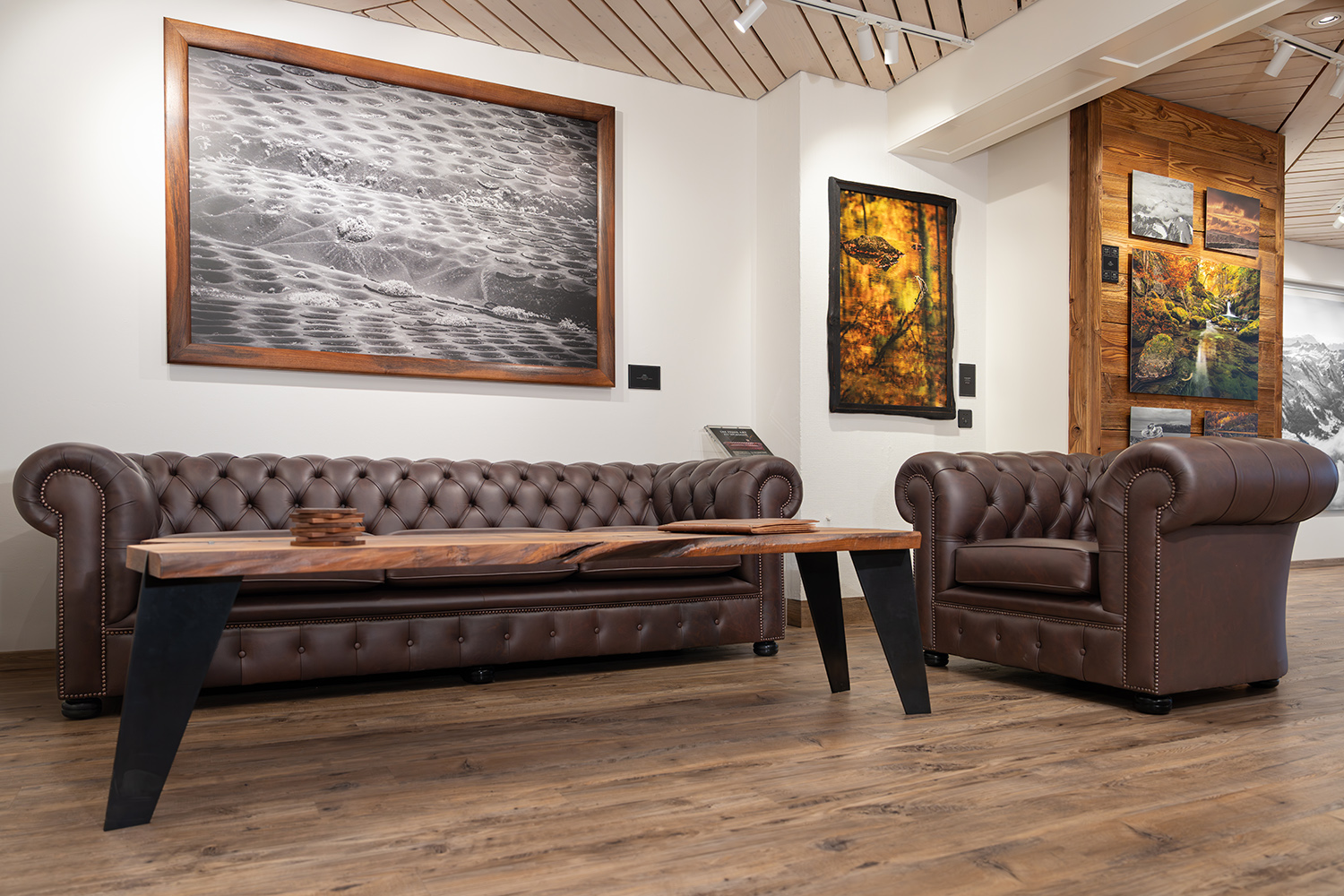 Innenansicht eines Raumes mit Ledersofa, Holztisch und gerahmter Kunstwerk