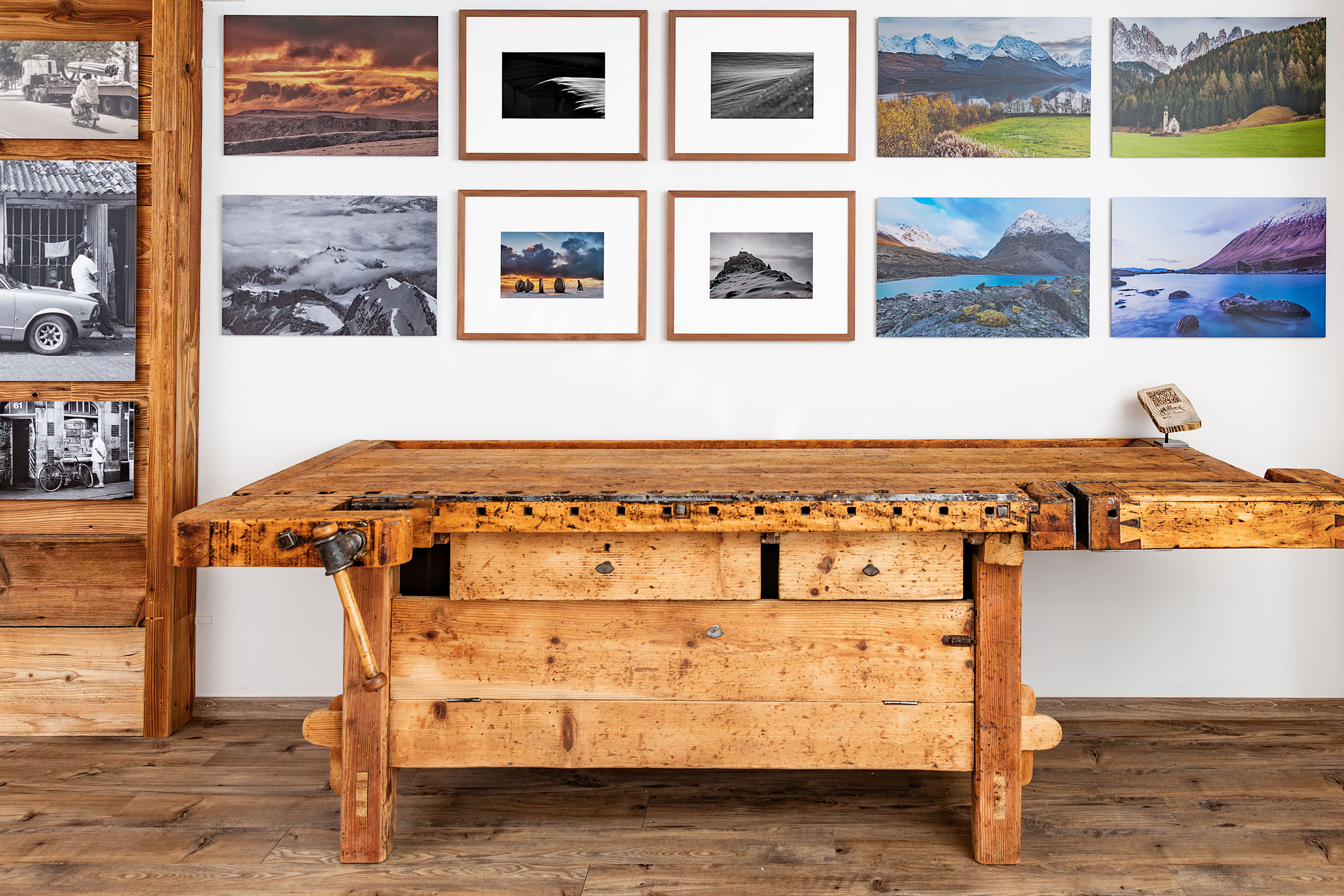 Werkstatt mit Holztisch und Galeriewand aus gerahmten Landschaftsfotografien