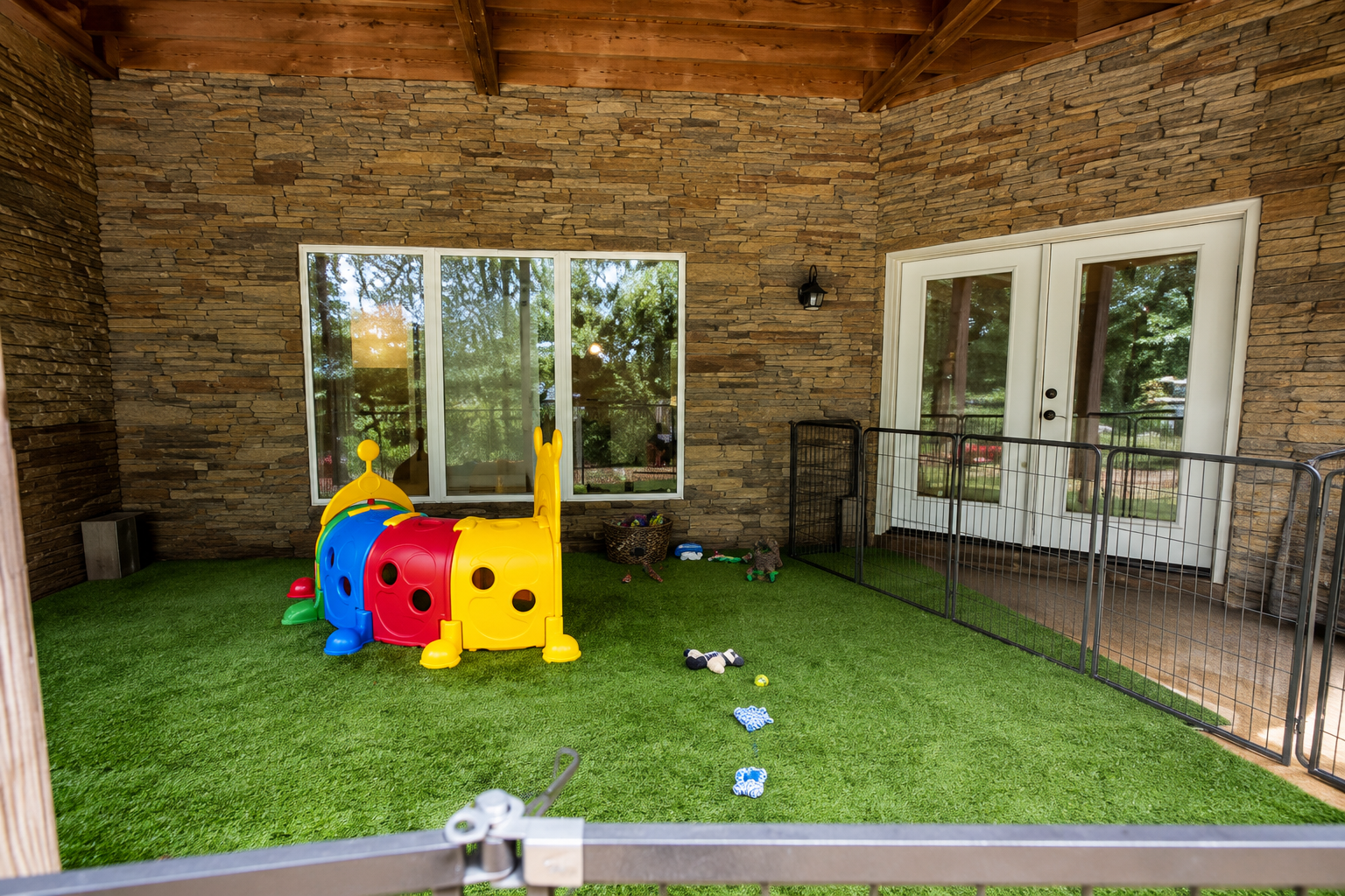 Stone-walled covered patio play area with colorful tunnels and toys