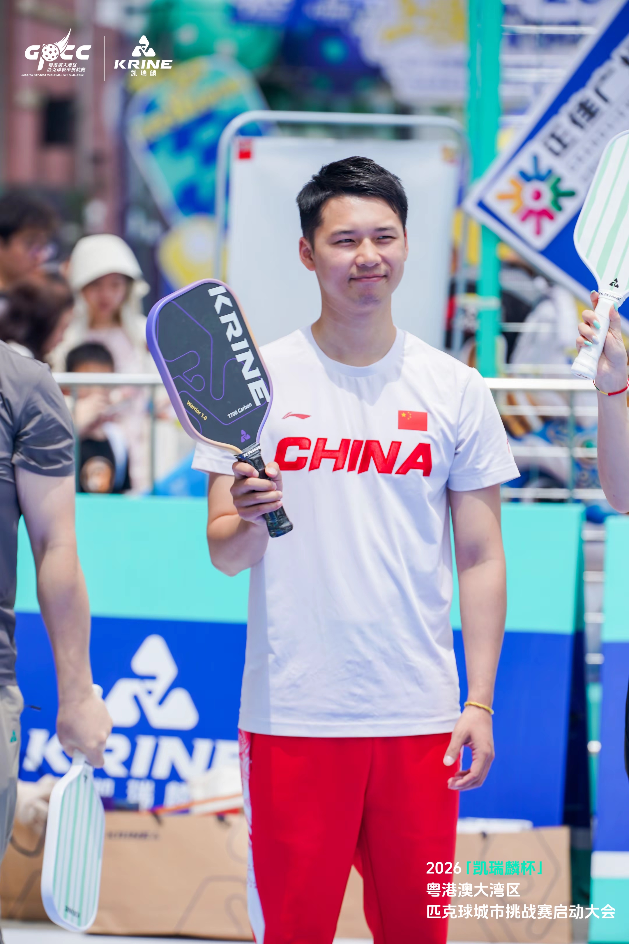 Player in a CHINA t-shirt holding a Krine pickleball paddle