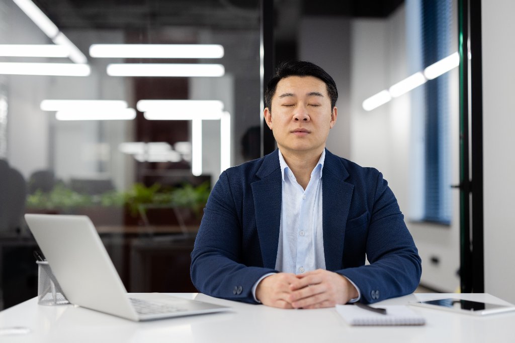 Professional meditating at office desk