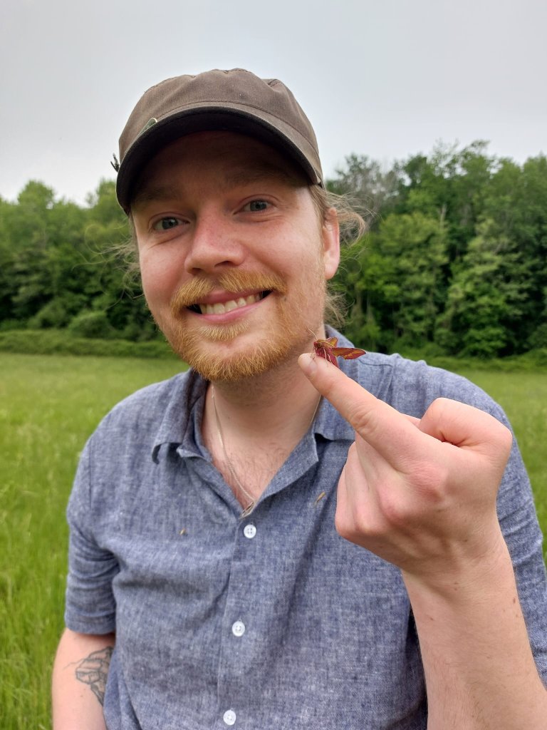 Jakob Wiil holding an insect in a meadow