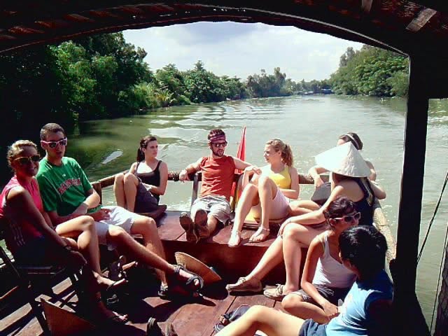 Group of participants enjoying a boat trip along a jungle-lined river