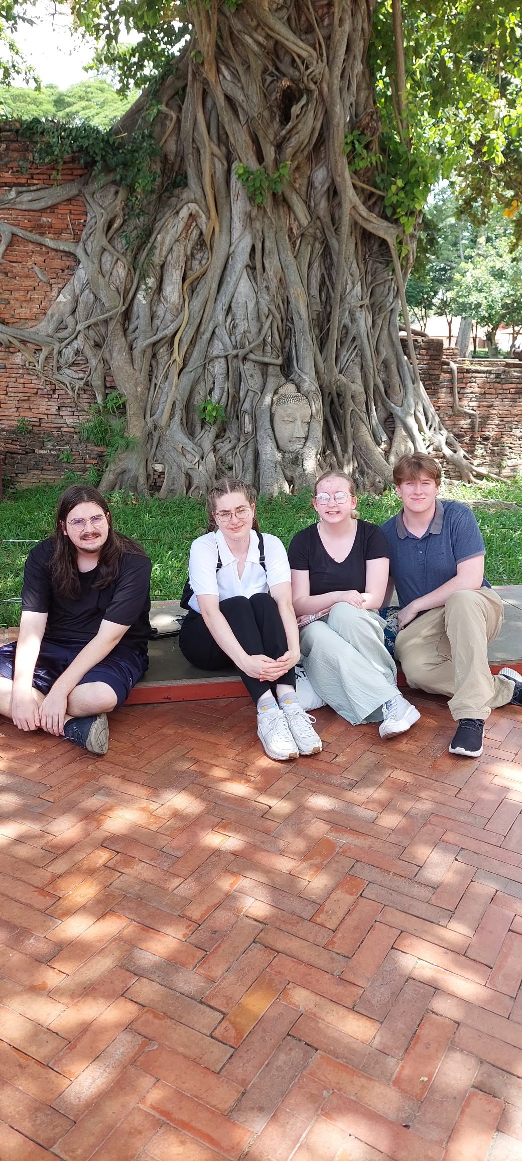 Group of participants at the famous Buddha head in banyan tree roots at Wat Mahathat, Ayutthaya