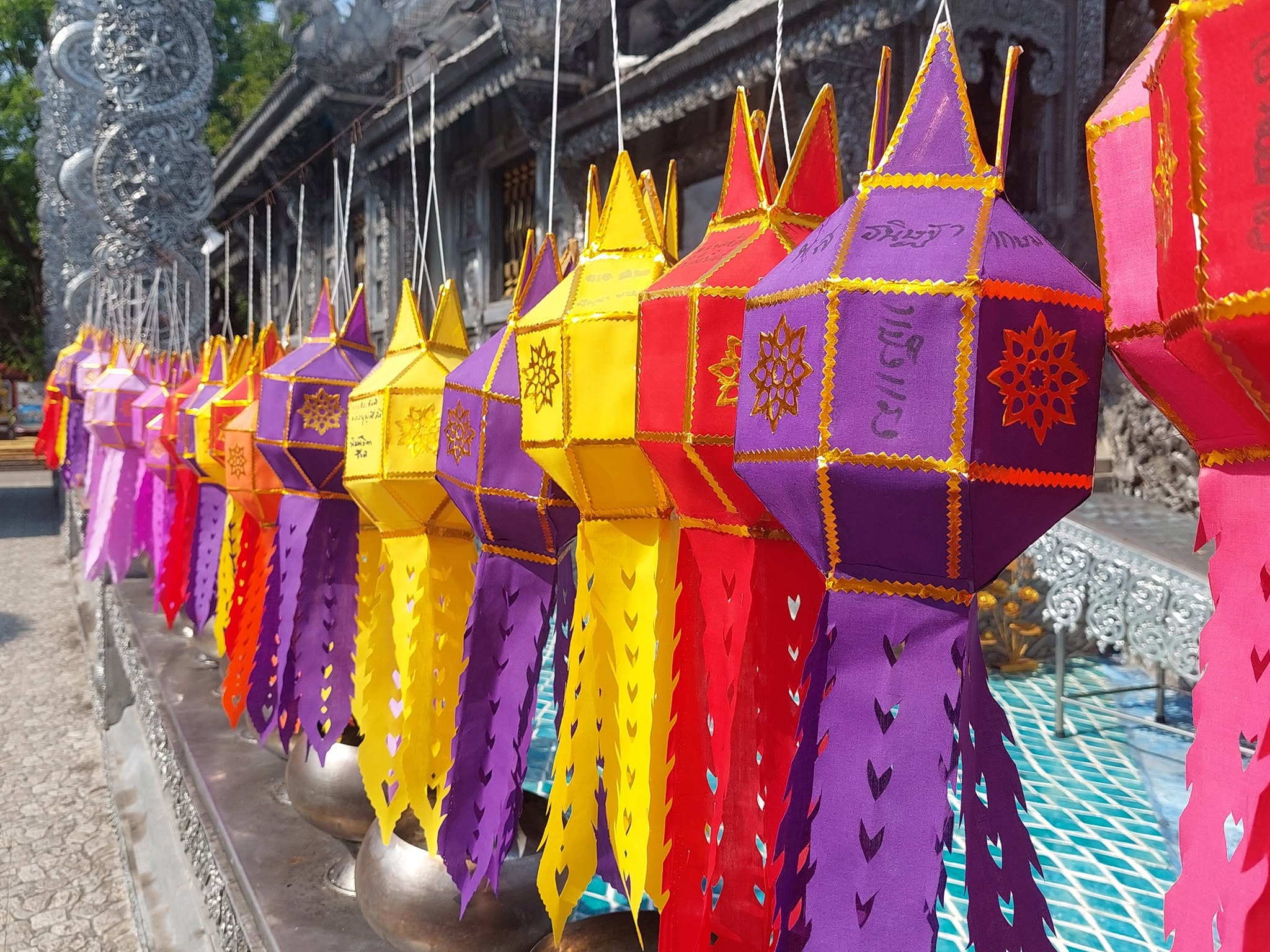 Row of colorful traditional Thai paper lanterns hanging in a line at a temple