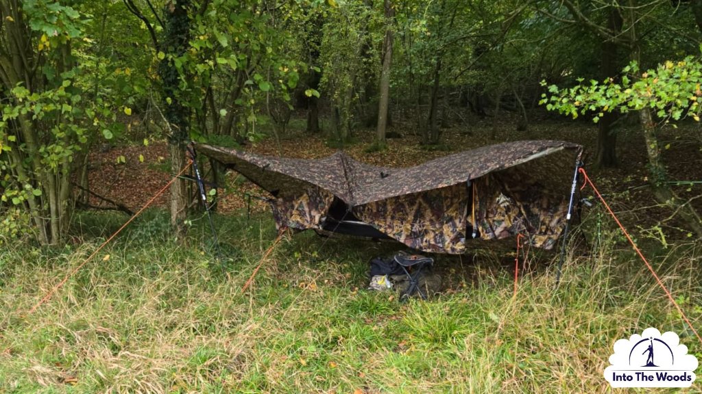 Prepping - camouflage tarp shelter rigged between trees in woodland