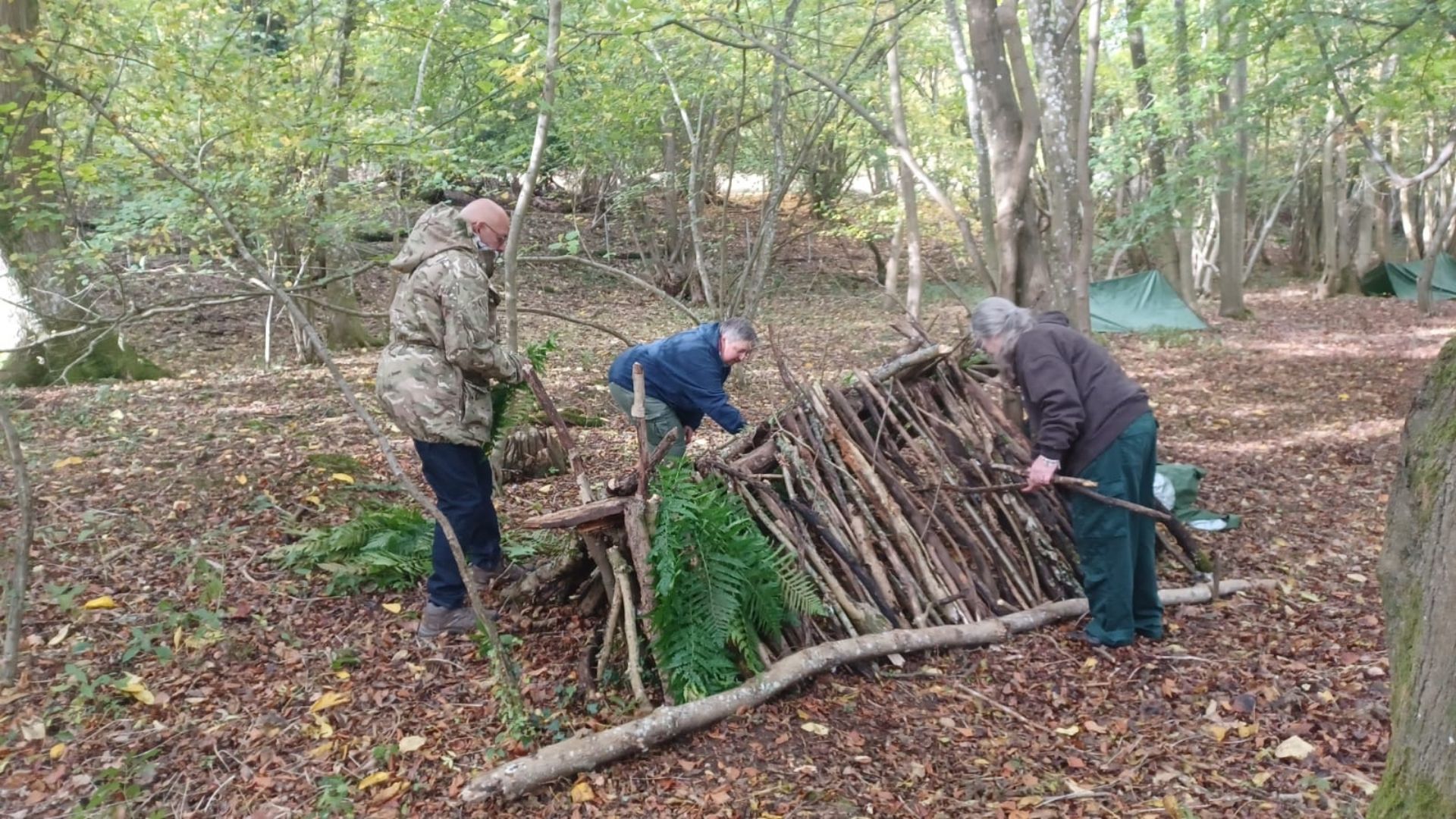 Group building shelter together at an Into The Woods charity fundraising event