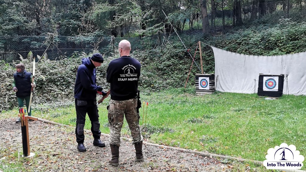 Archery - instructor guiding participant at archery range in woodland