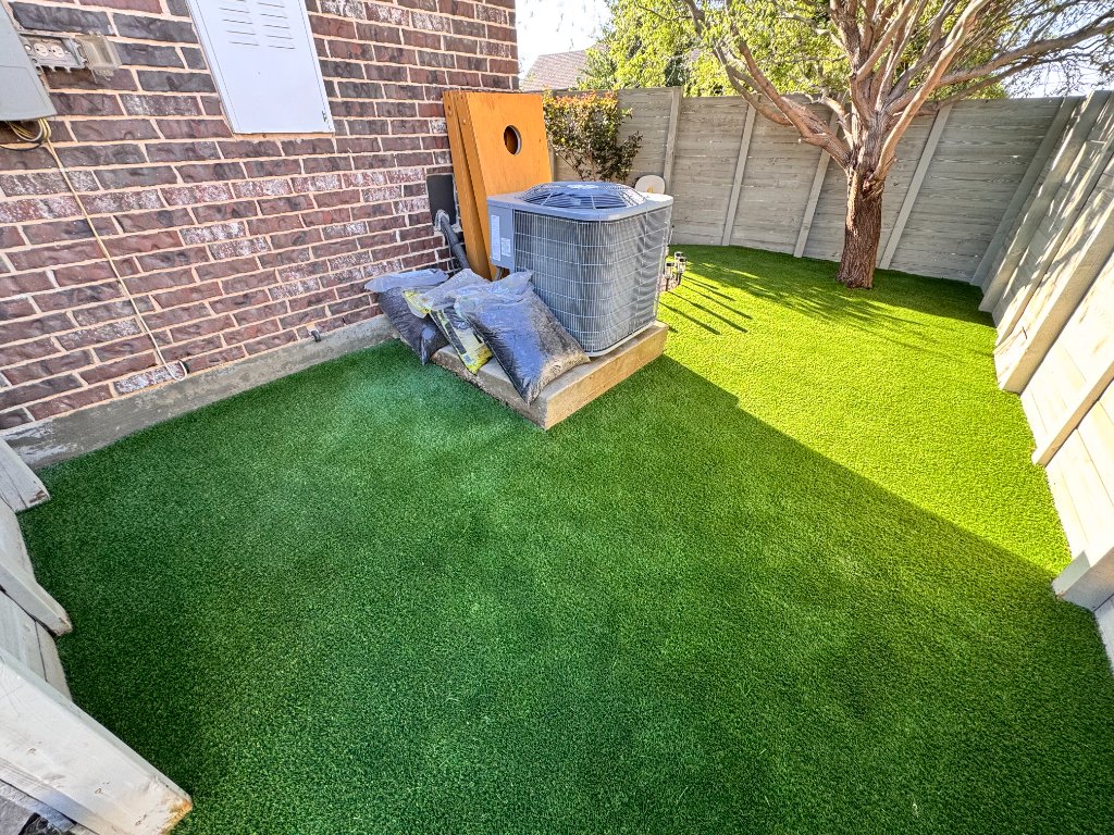 Artificial turf installed with clean edging along a brick wall