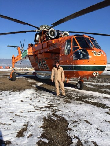 Gregory P. Smith standing in front of a large orange firefighting helicopter