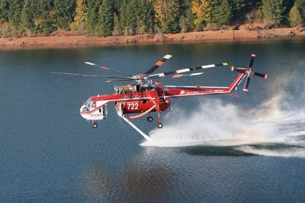 Firefighting helicopter scooping water from a lake during an aerial operation