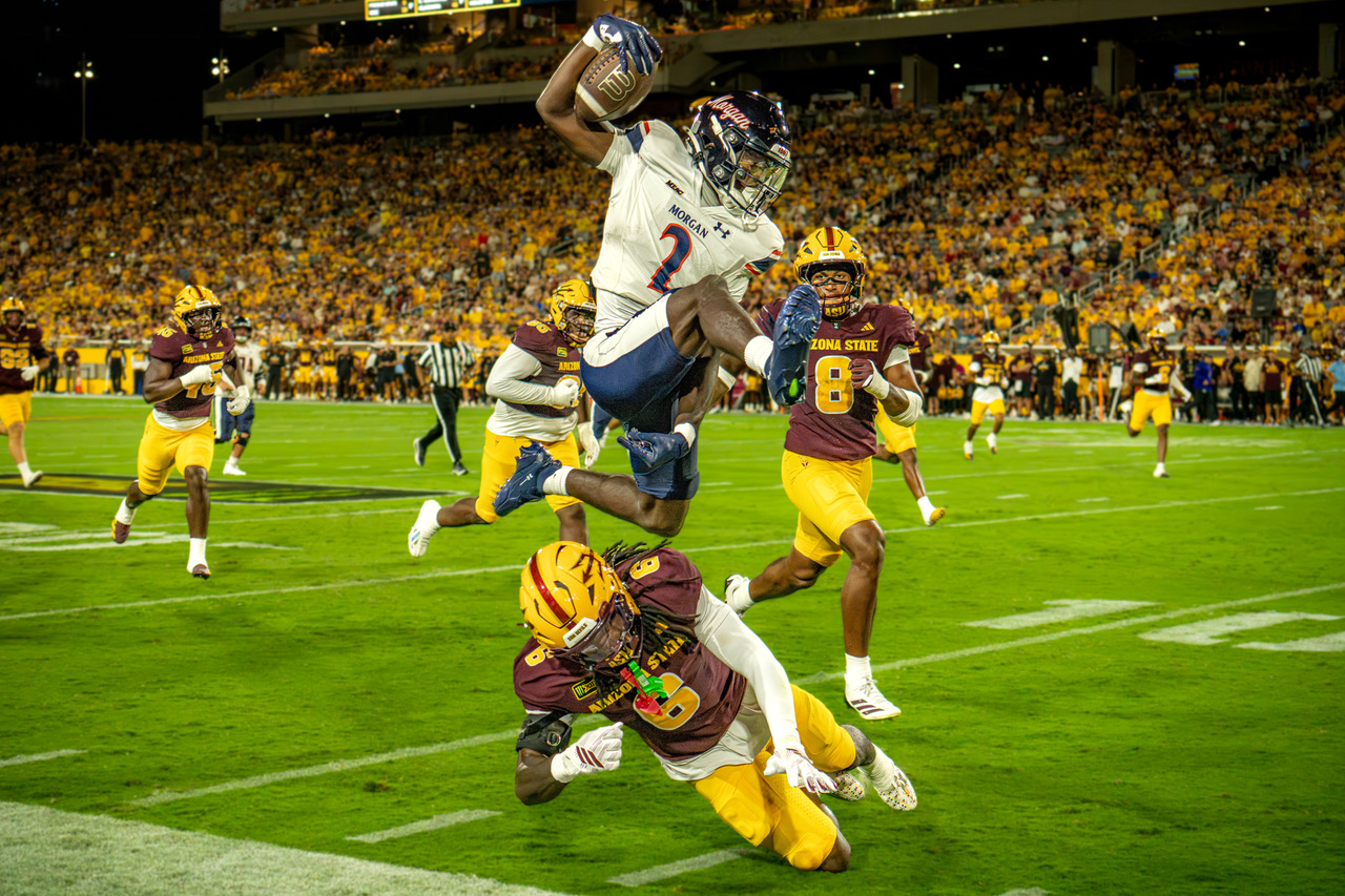 Morgan State ball carrier leaps over an Arizona State defender during a football game.