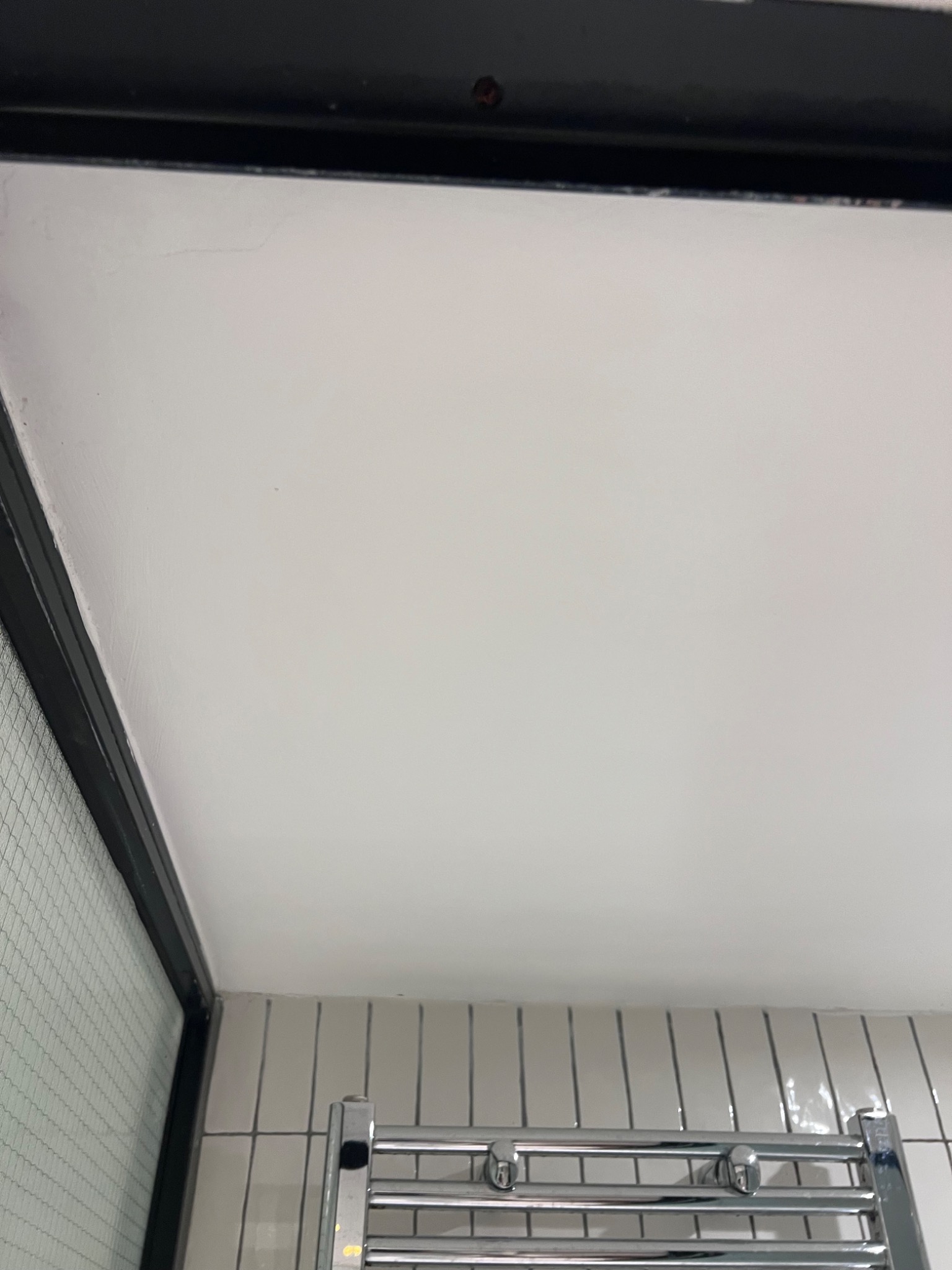 Smooth matte-white finished bathroom ceiling above tiled walls and chrome fixtures after a full damp-damage restoration